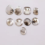 Assorted rose cut lab grown diamonds with natural-looking inclusions in oval, pear, round and cushion shapes arranged on white background for fine jewelry design.