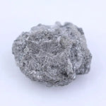 Natural black raw diamond embedded in rock with rough crystal structure and natural mineral texture