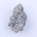Raw uncut diamond gemstone placed on neutral background showing natural clarity and texture