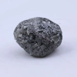 Close view of premium black diamond with bold dark sparkle and natural surface.