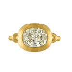 A gold ring featuring a large, cushion-cut clear gemstone in an oval bezel setting, shown against a plain white background.