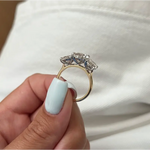 Three-stone oval diamond engagement ring in white gold on a woman’s hand with light blue manicure