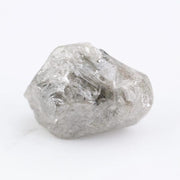 A rough, raw diamond held between metal tweezers against a clean white background.