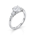 A silver-tone solitaire engagement ring featuring a cushion-cut diamond center stone and a pavé-set diamond accent on the band, shown on a clean white background.