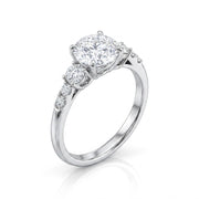 A silver-tone solitaire engagement ring featuring a cushion-cut diamond center stone and a pavé-set diamond accent on the band, shown on a clean white background.