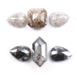 Assorted natural salt and pepper and white rustic diamonds in pear, hexagon, and elongated geometric cuts displayed on a white background, featuring visible inclusions and raw organic patterns.