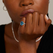 Luxury gemstone ring featuring vibrant colored stone with dazzling white stone halo des