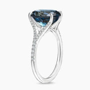 Luxury gemstone ring featuring vibrant colored stone with dazzling white stone halo des