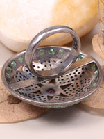 Silver ring with gemstones on a white surface with leaves