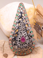 Ornate pendant with gemstones on a stone and leaf background