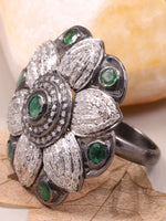 Silver ring with green gemstones on a leaf and stone background