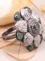 Silver ring with green gemstones on a leaf and shell background