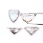 Four salt and pepper lab grown diamonds in shield, trillion, and geometric fancy cuts with natural grey inclusions, displayed on white background as loose ethical conflict-free stones for custom jewelry.