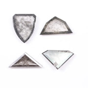 Four salt and pepper lab grown diamonds in shield, trillion, and geometric fancy cuts with natural grey inclusions, displayed on white background as loose ethical conflict-free stones for custom jewelry.