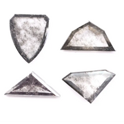 Four salt and pepper lab grown diamonds in shield, trillion, and geometric fancy cuts with natural grey inclusions, displayed on white background as loose ethical conflict-free stones for custom jewelry.
