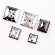 Five square step-cut lab grown diamonds with pyramid-style faceting and visible natural inclusions displayed on a white background, featuring clear, salt and pepper, and champagne tones.