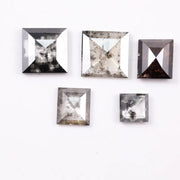 Five square step-cut lab grown diamonds with pyramid-style faceting and visible natural inclusions displayed on a white background, featuring clear, salt and pepper, and champagne tones.