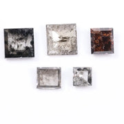 Five square step-cut lab grown diamonds with pyramid-style faceting and visible natural inclusions displayed on a white background, featuring clear, salt and pepper, and champagne tones.