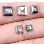 Five square step-cut lab grown diamonds with pyramid-style faceting and visible natural inclusions displayed on a white background, featuring clear, salt and pepper, and champagne tones.