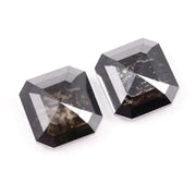 Pair of emerald cut salt and pepper lab grown diamonds with black and white inclusions in geometric step cut, shown loose on white background.