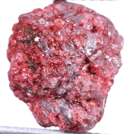 Raw red diamond held by tweezers on a white background