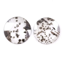 Two round brilliant cut lab grown diamonds with black galaxy-style inclusions on white background, faceted loose stones for custom fine jewelry.