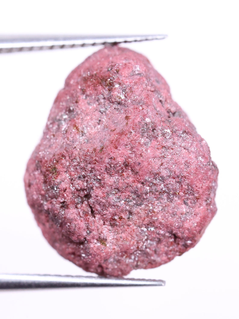 Pink diamond held between tweezers on a white background