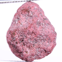Pink diamond held between tweezers on a white background
