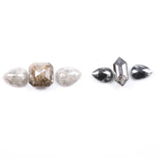 Assorted natural salt and pepper and white rustic diamonds in pear, hexagon, and elongated geometric cuts displayed on a white background, featuring visible inclusions and raw organic patterns.