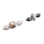 Assorted natural salt and pepper and white rustic diamonds in pear, hexagon, and elongated geometric cuts displayed on a white background, featuring visible inclusions and raw organic patterns.