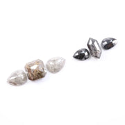 Assorted natural salt and pepper and white rustic diamonds in pear, hexagon, and elongated geometric cuts displayed on a white background, featuring visible inclusions and raw organic patterns.
