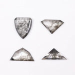 Four salt and pepper lab grown diamonds in shield, trillion, and geometric fancy cuts with natural grey inclusions, displayed on white background as loose ethical conflict-free stones for custom jewelry.