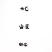 Six natural black diamonds in geometric cuts including star, kite, emerald rectangle, pentagon, and round brilliant shapes displayed on white background.