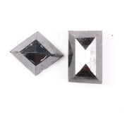 Pair of natural black diamonds featuring a shield-shaped cut and an elongated baguette-style cut, loose matching set with faceted surfaces for custom fine jewelry design.