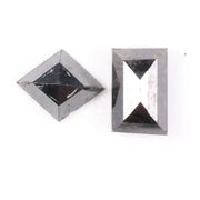 Pair of natural black diamonds featuring a shield-shaped cut and an elongated baguette-style cut, loose matching set with faceted surfaces for custom fine jewelry design.