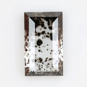 Rectangular step cut lab grown diamond featuring dramatic black dendritic inclusions in a salt and pepper pattern, creating a unique one of a kind modern alternative diamond with striking natural looking carbon formations inside a clear faceted stone.