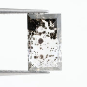 Rectangular step cut lab grown diamond featuring dramatic black dendritic inclusions in a salt and pepper pattern, creating a unique one of a kind modern alternative diamond with striking natural looking carbon formations inside a clear faceted stone.