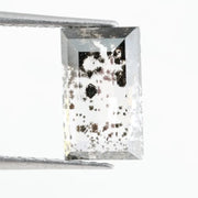 Rectangular step cut lab grown diamond featuring dramatic black dendritic inclusions in a salt and pepper pattern, creating a unique one of a kind modern alternative diamond with striking natural looking carbon formations inside a clear faceted stone.