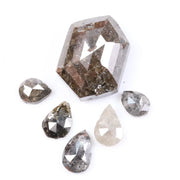 Set of natural salt and pepper diamonds including one hexagon cut center stone and five pear-shaped diamonds with visible inclusions and earthy brown, gray, and translucent tones on white background.