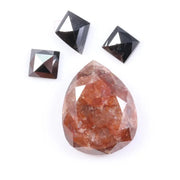 Large natural pear-shaped orange diamond with visible inclusions, surrounded by three black geometric-cut natural diamonds on a white background.