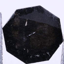 Black octagon lab grown between two tweezers on a black background