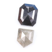 Natural black octagon-cut diamond and shield-cut salt-and-pepper diamond displayed on white background, showing unique inclusions and rustic faceting details.