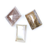 Three natural diamonds including a pink included fancy cut diamond, a golden brown heavily included diamond, and a clear step cut rectangular natural diamond displayed on a white background.