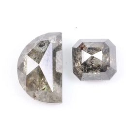 Pair of natural salt and pepper diamonds featuring a half moon rose cut and an octagonal step cut, both with visible grey and black inclusions and a rustic translucent appearance on a white background.