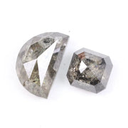 Pair of natural salt and pepper diamonds featuring a half moon rose cut and an octagonal step cut, both with visible grey and black inclusions and a rustic translucent appearance on a white background.