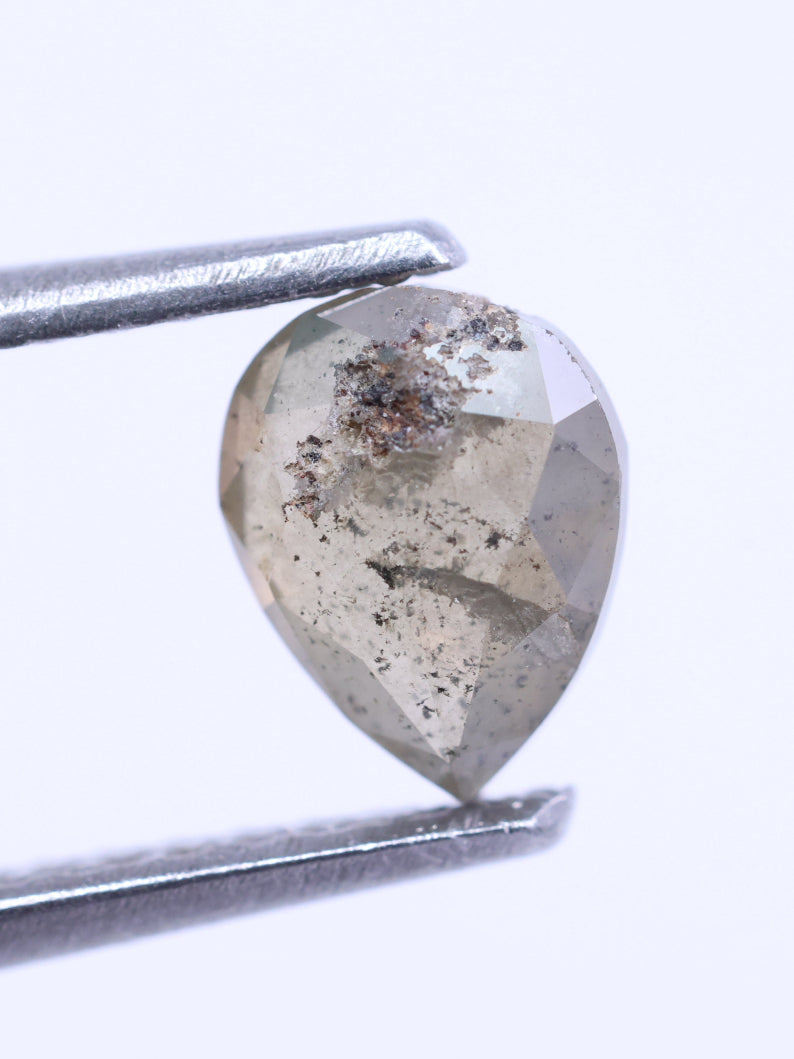 pear-shaped diamond held by tweezers on a white background