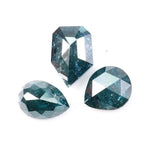 Three natural teal blue diamonds featuring pear, oval, and shield cuts with visible galaxy-like inclusions, rare salt and pepper natural diamonds ideal for custom jewelry design