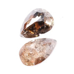 Pair of natural brown diamonds showing raw crystal inclusions and faceted pear shapes with cognac tones, genuine earth mined gemstones with natural internal patterns and rough texture ideal for collectors, jewelers, and natural diamond enthusiasts.