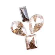Natural brown salt and pepper diamond set featuring two pear shaped diamonds and two baguette step cut diamonds with visible natural inclusions and rustic champagne tones for custom jewelry design.
