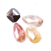 Collection of natural fancy color diamonds including pink, yellow, champagne and cognac loose diamonds with faceted cuts displayed on white background for fine jewelry and gemstone collecting.